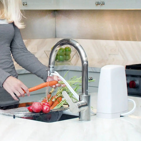 Woman washing vegetables with Replacement Filter Cartridge For Countertop Water Filtration System That Delivers Crisp Tasting Water