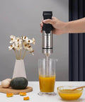 Heavy Duty 1000W Immersion Blender With 20 Speed Settings Ergonomic Grip Electric Hand Mixer blending soup in a clear measuring jug.