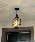 Top Tier 15 Inch Outdoor Indoor Pendant Light Featuring Heavy Duty Black Metal And Thick Water Seeded Glass hanging in entryway.