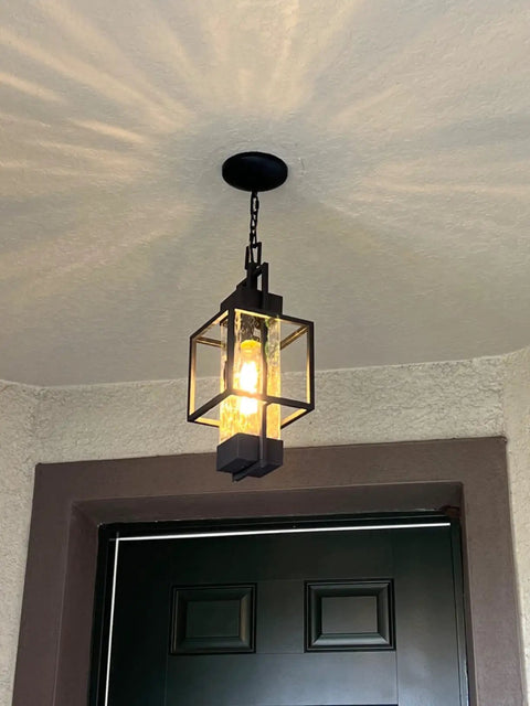 Top Tier 15 Inch Outdoor Indoor Pendant Light Featuring Heavy Duty Black Metal And Thick Water Seeded Glass hanging in entryway.