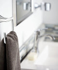 Wall-mounted bathroom faucet and towel holder in modern bathroom setting with mirror