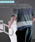 User holding sturdy 31.4 inch stainless steel handicap grab bar wall mounted with flip up toilet rail for shower and bath safety.