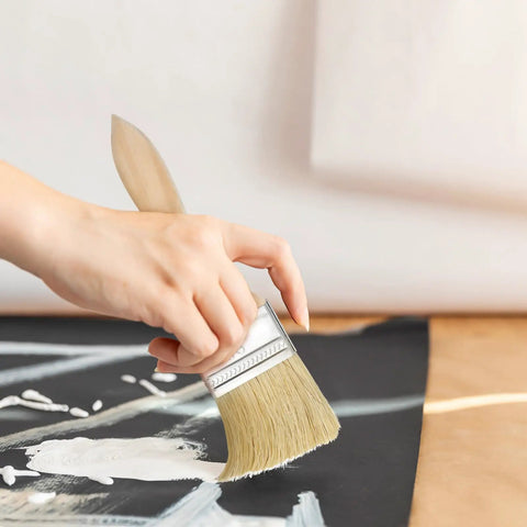 Hand holding a brush from 30 Piece Thick Wood Handle Paint Brush Set For Stain And Varnish Heavy Duty Bristles For Walls Decks And Fences Built For Big Jobs