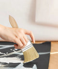 Person using 30 Piece Deck Oil Paint Brush Set Pro Grade With Thick 12mm Wood Handles on black canvas surface.