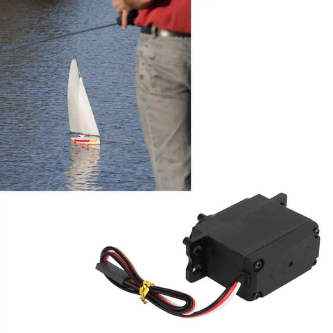 Beefy Metal Gear Sail Winch Servo Motor With Alloy Gears Analog Servo in black, shown near a model sailboat on water surface.