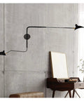 Slick Adjustable Double Head Wall Sconce Lamp In Modern Black Finish With Swivel Pole Design mounted on a concrete wall.