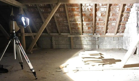 4,000 Lumen 18V Bluetooth LED Floodlight illuminating an attic space, mounted on a tripod, remote control feature