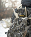 Hunter wearing Pro 1075 Backpack in Mossy Oak Bottomland Camo with antlers, wide padded shoulders, ideal for quiet hunting.