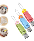 3-piece cup lid gap cleaning brush set with flower-topped handles in pink, blue, and green; angled side view.