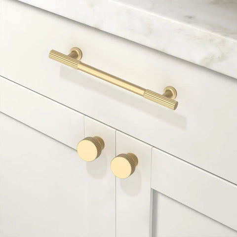 Close-up of Five Pack Brushed Gold Cabinet Pulls Five Inch Kitchen Cabinet Handles Hardware for drawers installed on white cabinet.