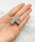 Glittery silver rhinestone bow in hand, perfect for adding charm to DIY jewelry crafting or accessories.
