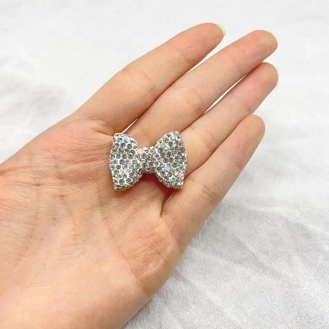 Glittery silver rhinestone bow in hand, perfect for adding charm to DIY jewelry crafting or accessories.