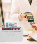 Portable Rechargeable Cash Counting Machine With UV And MG Counterfeit Detection in use at checkout counter