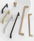 Various cabinet handles in different finishes, including brushed satin nickel, arranged on a textured surface.