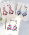 Polymer clay floral earrings displayed on cards with Keoker branding.