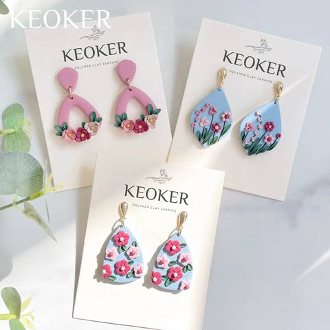 Polymer clay floral earrings displayed on cards with Keoker branding.