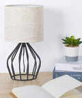 Black Modern Table Lamp With Linen Fabric Shade And Hollowed Base on desk, compact bedside light near books and plant