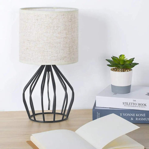 Black Modern Table Lamp With Linen Fabric Shade And Hollowed Base on desk, compact bedside light near books and plant