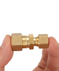 Brass compression union tube fitting 3/8 in to 1/4 in tube OD, held between fingers.
