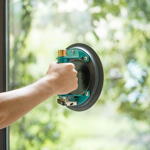 Hand using 8 Inch Vacuum Suction Cup For Granite And Glass Lifting with Metal Handle and Brass Pump on glass surface