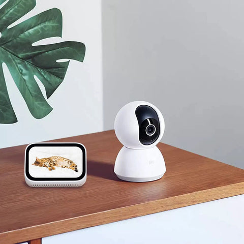 360 Degree All-In-One Home Security Cam 2K With AI Human Detection on wooden table next to digital pet monitor.