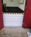 Heavy Duty Aluminum Flood Shields For Doors And Warehouse Openings, installed at a door with yellow caution stripes.