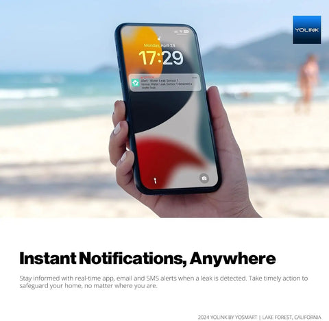 Smartphone displaying leak alert from FlowSmart All-In-One Smart Water Meter, held at the beach with ocean in background.