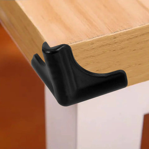 Black silicone corner guard on wooden table edge, part of Silicone Corner Guards 4 Pack For Furniture And Tables, Easy To Install Edge Bumpers