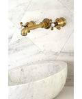 8-Inch Center Wall Mount Bathroom Faucet in Brushed Brass with European-Inspired Detailing, installed above marble basin