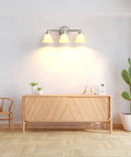 Dope Three Light Chrome Vanity Light Fixture With Frosted Glass Shades mounted on wall above wooden console in modern room.