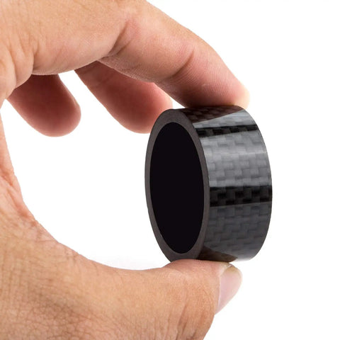 Hand holding a carbon fiber bike headset spacer from Carbon Fiber Bike Headset Spacers Set For One And One Eighth Inch Stems 12 Pieces Including 1mm 2mm 3mm 5mm 10mm 15mm Spacers Lightweight Durable Front Fork Spacers For Adjustable Handlebar Height Easy Fit.