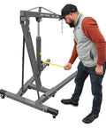 Heavy Duty Folding Shop Crane With Hydraulic Engine Hoist Six Wheel Base And Safety Brakes Badass Steel Frame For Auto Mechanics shown in use.