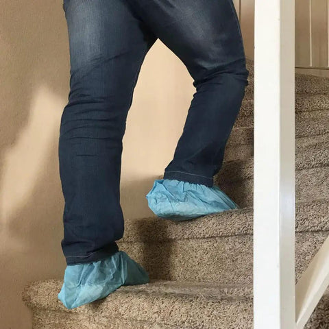 Person wearing blue Disposable Shoe Covers X Large on stairs for floor protection, fits men's 14 and women's size boots 11-13
