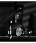58mm Dosing Funnel And Coffee Distributor For Espresso Portafilter Holder With Adjustable Stainless Steel Tamper and Bottomless Stand shown in black with metallic accents.