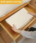 Person folding Soft Large Canvas Storage Bags With Zipper And Clear Window For Pillows, Quilts, Blankets And Comforters, 80L Each, 4 Pack Beige Cotton Linen Organizer Bins For Home Closets into a drawer