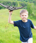 Child playing with B-2 Spirit Stealth Bomber RC Airplane Ready To Fly 2.4GHz 2CH Foam Drone in grassy field