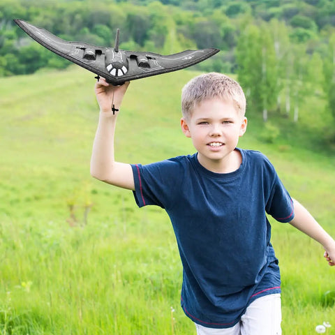 Child playing with B-2 Spirit Stealth Bomber RC Airplane Ready To Fly 2.4GHz 2CH Foam Drone in grassy field
