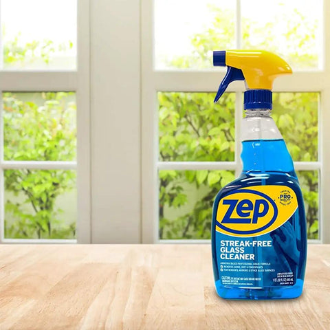 Streak Free Glass Cleaner 32 Oz Pro Grade Formula for Windows and Surfaces in blue bottle on wooden table by window.