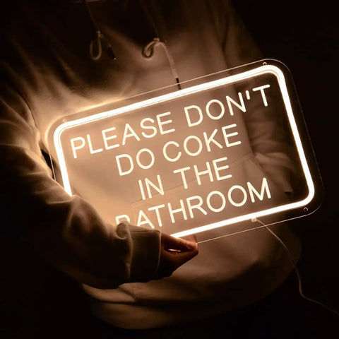 Person holding 'Please Don't Do Coke In The Bathroom LED Neon Sign USB Powered For Bedroom Game Room Bar Or Home Decor 15.8 By 9.8 Inches With 6.6 Ft USB Cord And Dimmer'