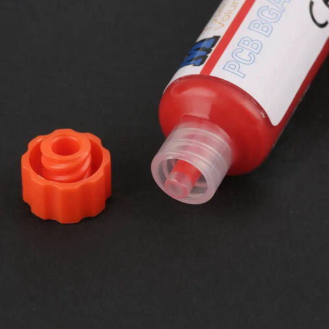 Flux Repair Kit With Light Curing Liquid No Clean Flux For PCB BGA Boards Includes Precision Needles And Flashlight For Quick Easy Solder Paste Fixes Like A Pro Today. Close-up of open red flux tube with orange cap on black background.