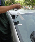 Person applying Heavy Duty Waterproof Duct Tape 2 Inch By 30 Yards Six Roll Multipack to car windshield for repair