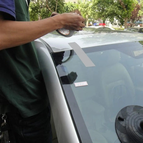 Person applying Heavy Duty Waterproof Duct Tape 2 Inch By 30 Yards Six Roll Multipack to car windshield for repair