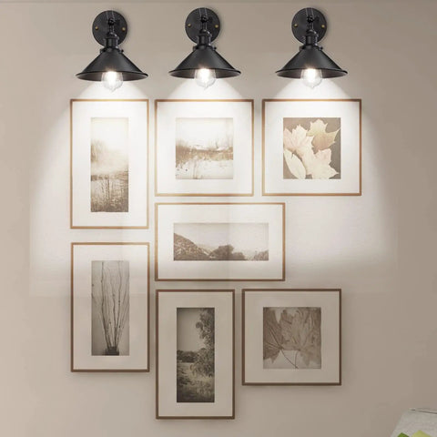 Three black industrial wall sconces with gooseneck lighting illuminating framed art, Two Pack Black Industrial Wall Sconces With Adjustable Gooseneck Lighting