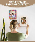 Person hanging Fun DIY Mosaic Photo Frame Kit For 4x6 Photos 8 Unfinished Wooden Frames With Mosaic Tiles And Included Glue Finger Cots And Spreader Tools For Easy Home Craft And Personalized Photo Displays on wall.