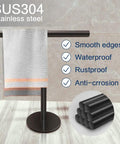 Hand Towel Holder Stand For Bathroom Vanity Countertop Matte Black Finish Free Standing Design Space Saving Movable T Shape Towel Bar Rack For Kitchen And Bath with towel displayed on tile surface.