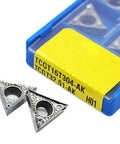 Two triangular carbide turning inserts with center hole beside a blue storage case labeled TCGT16T304-AK H01