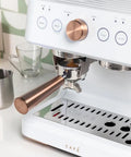 Next Level Semi Automatic Espresso Machine With Badass Built In Grinder And Silky Milk Frother Featuring WiFi App Control Custom Drinks 15 Bar Pump 95 Oz Water Tank Matte White Copper Accents close-up of portafilter, gauge, and copper accents
