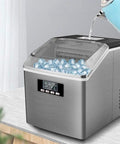 Hella Quick Electric Ice Cube Maker Turns Out Twenty Four Drink Ready Cubes In Under Fifteen Minutes in use with water pouring in.