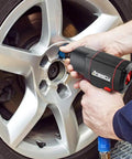 Person using Beast Of A Half-Inch Air Impact Wrench With Twin Hammer, 1700 Nm Max, on a car wheel with composite body and soft grip.