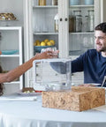 Two people at a table with Extra Clean Water Tank For Countertop Reverse Osmosis System - BPA Free, Shatterproof, Pitcher Style Tank.